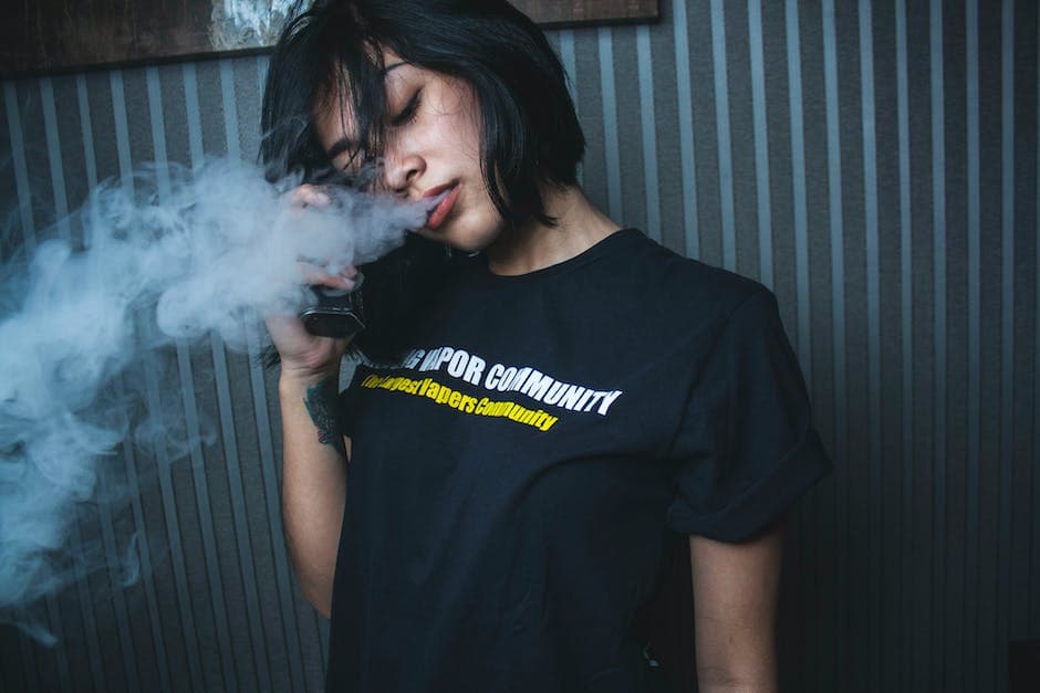 Thoughtful young woman vaping in dark room