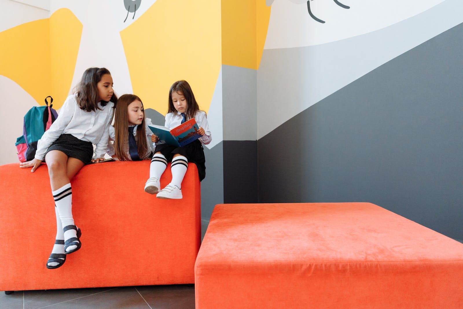 Three Girls in School Uniforms Reading a Book