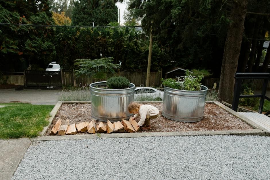 Child working with firewood near flowerbed in small backyard