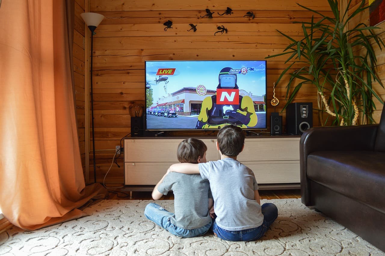 kids are watching television on the ground, arms around each other